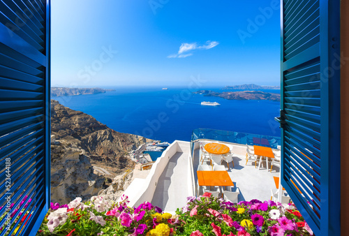 Open window with shutters overlooking a whitewashed tourist resort area, blue sea and the cruise port at Thera, Greece, on the island of Santorini.