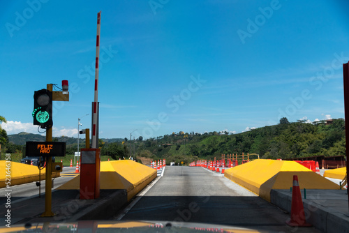 Automatic gate barrier open for vehicular passage at a Colombian highway toll. photo