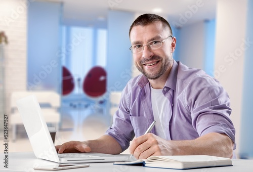 Satisfied man looking at computer screen, reading good news in email, chatting in social network with friends, freelancer blogger working on online project