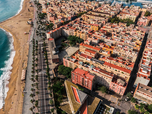 Drone shot Barcelona. Port with boats near the coast. Drone view of a vibrant swimming and sunbathing beach in Barcelona. People are relaxing on the beach. Panoramic view of the city of Barcelona.