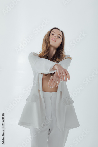 Woman in white suit on white background. Fashion portrait