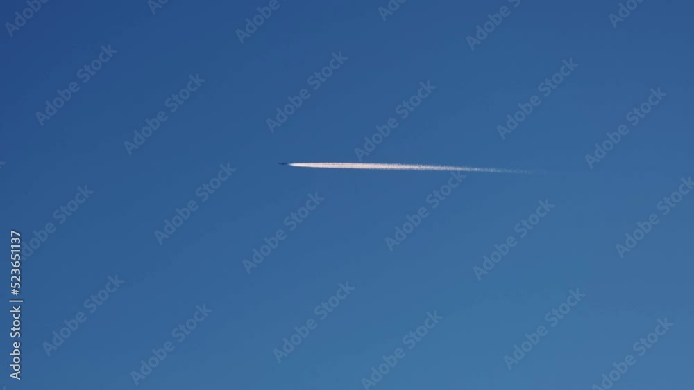 Airplane with white trail line against the clear deep blue sky on a sunny day. Looking up. Modern technology, tourism, transportation, aviation concept with copy space. 4K Airplane with white trail line against the clear deep blue sky on a sunny day. Looking up. Modern technology, tourism, transportation, aviation concept with copy space. 4K