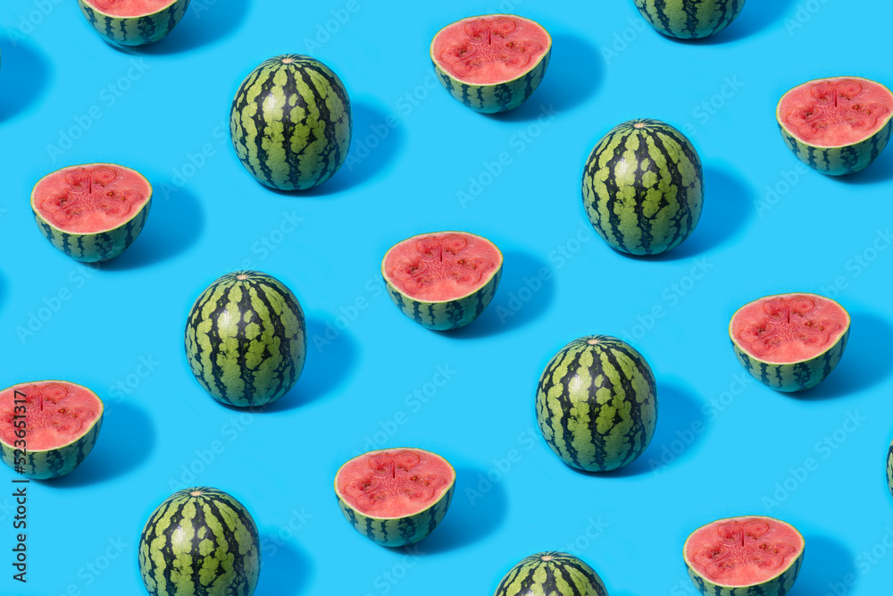 Pattern of mini watermelons and slice watermelon halves on a blue background.