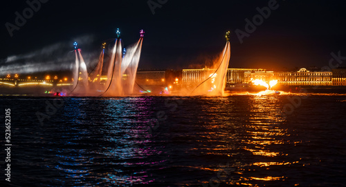 A lot of flyboarders and brightly dressed up jet skiers perform their show at a holiday in the center of St. Petersburg at night, water activities