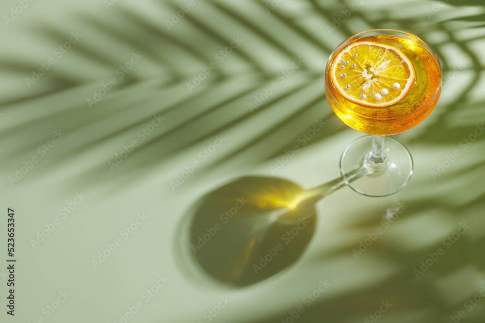 summer refreshing cocktail on a light green background with a shadow from a palm tree, top view