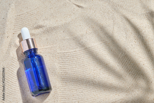 Fotografía face serum of glass bottle with a pipette on a natural background with sand