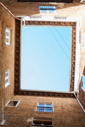 Blue sky seen from an inner courtyard where windows are visible
