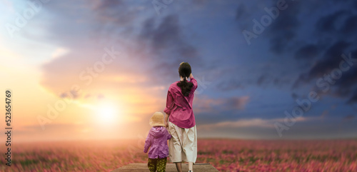 a mother with her child in a summer flower field at sunset. happy family and summer concept.
