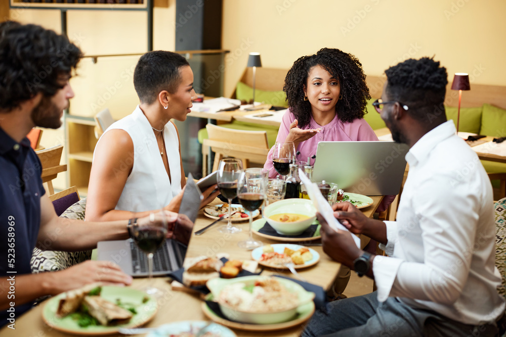 The businesspeople sit in a restaurant and have a business meeting during dinner.