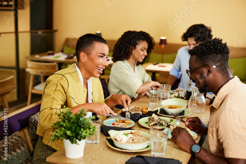 A group of cheerful friends are eating dinner in a restaurant.