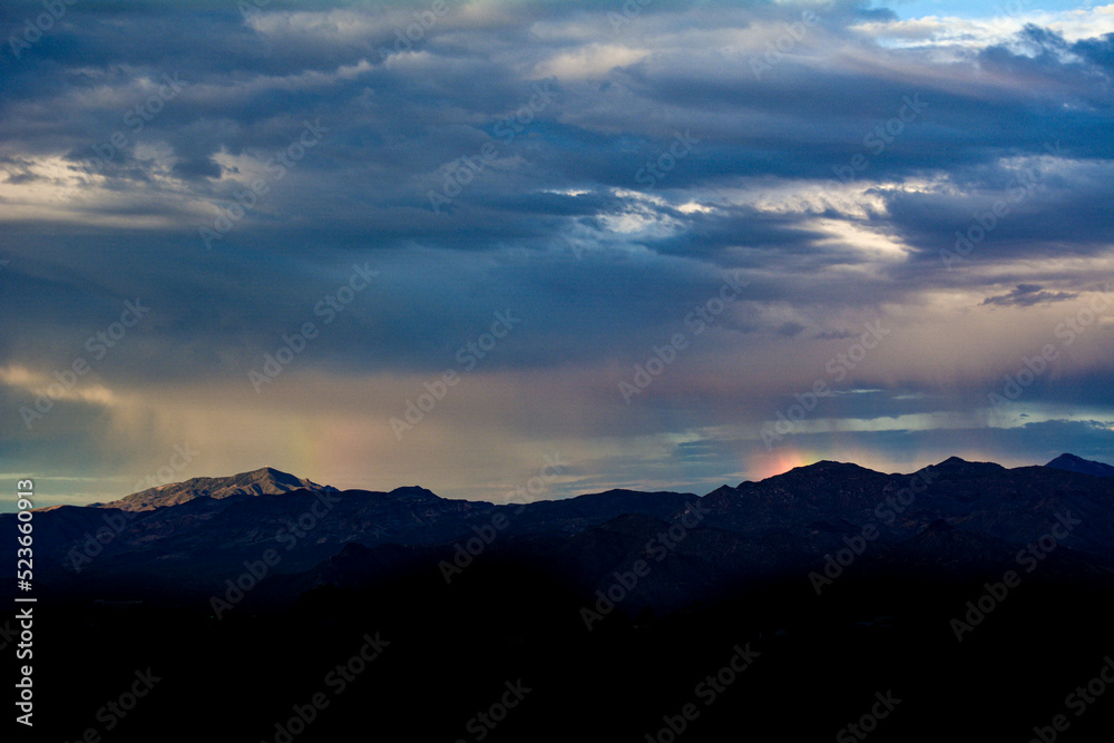 Rain falling on the Arizona Mountain Range with Sun Dog Rainbow Reflection in Clouds