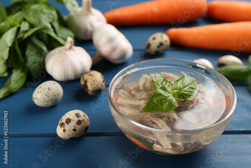 Delicious aspic with meat in bowl on blue wooden table photo