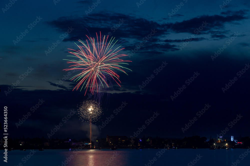 Fireworks celebration with reflections across the river with a town in the background