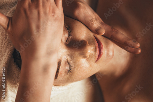 Beautiful freckled woman getting a face massage at beauty salon.