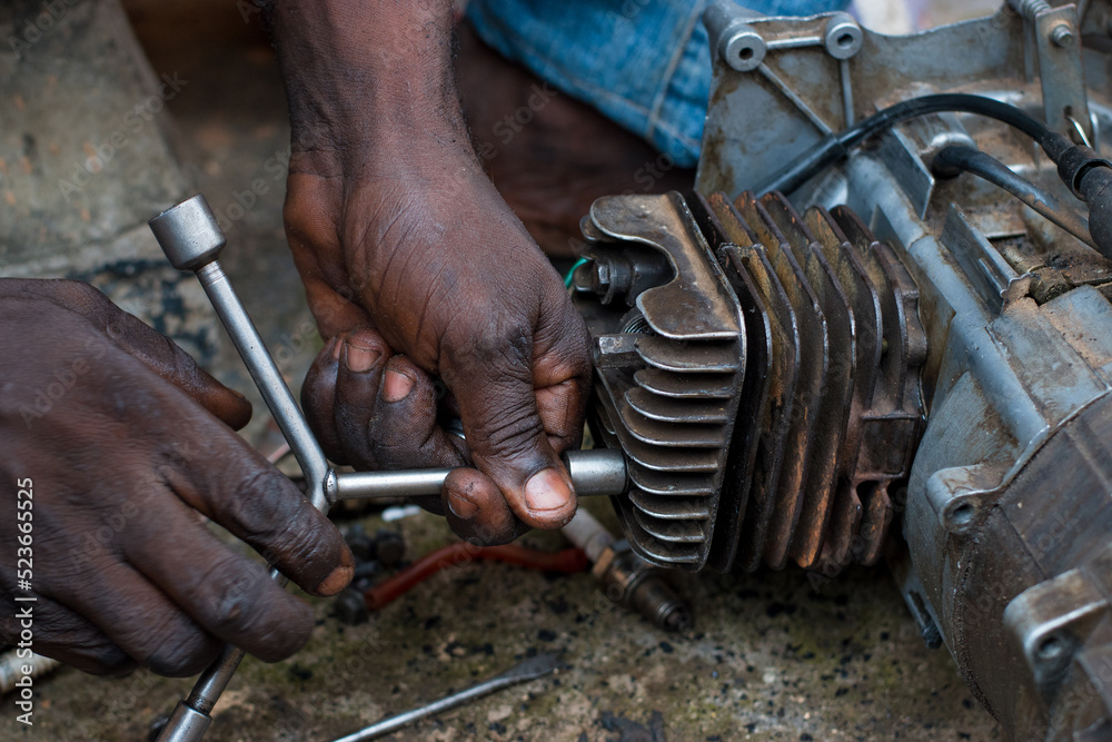An Engineer working on a small electricity generator in an engineering workshop, undergoing repair and maintenance for better generation of electrical energy for household and business in Nigeria An Engineer working on a small electricity generator in an engineering workshop, undergoing repair and maintenance for better generation of electrical energy for household and business in Nigeria