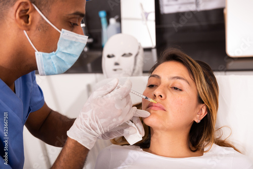 Portrait of peruvian female client of modern clinic of aesthetic cosmetology during procedure of face mesotherapy. Beauty injections