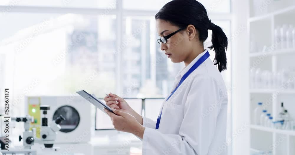 Serious female scientist working and writing patient information in a lab. Laboratory worker looking at and analyzing health data for a science journal. Medical professional doing a clinical trial Serious female scientist working and writing patient information in a lab. Laboratory worker looking at and analyzing health data for a science journal. Medical professional doing a clinical trial