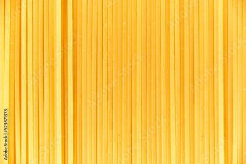 Italian food background, macro image of raw spaghetti filling the frame in a textured design of vertical pasta lines.