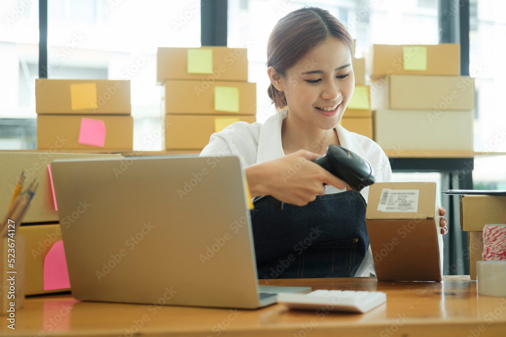 Young asian businesswoman use bar code scanner Scan the barcode on the product box. Young asian businesswoman use bar code scanner Scan the barcode on the product box.