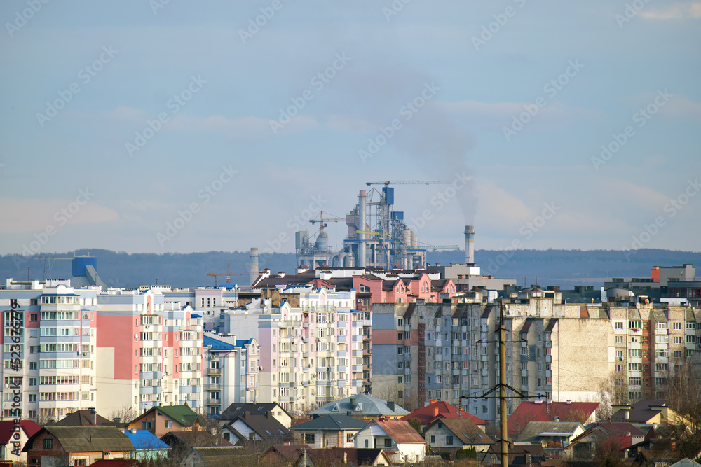Cement plant with high factory structure and tower cranes at industrial production area near city urban area. Manufacture and global industry concept Cement plant with high factory structure and tower cranes at industrial production area near city urban area. Manufacture and global industry concept