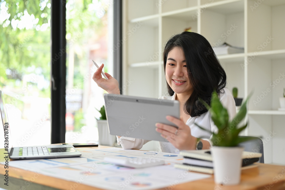 Asian businesswoman planning her financial investment strategy on a digital tablet. Asian businesswoman planning her financial investment strategy on a digital tablet.