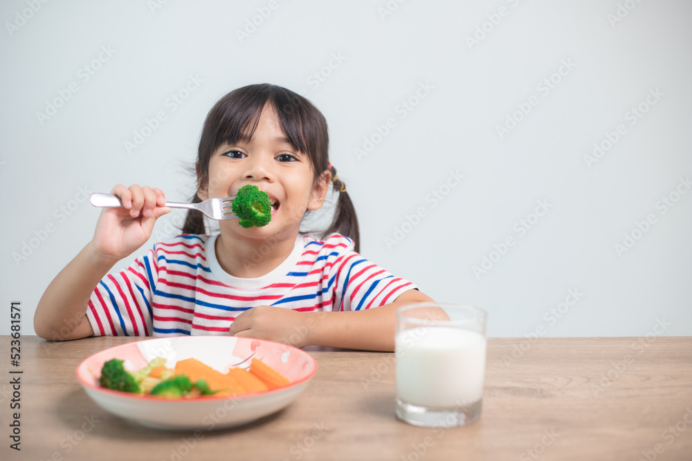 Cute asian child girl eating healthy vegetables and milk for her meal Cute asian child girl eating healthy vegetables and milk for her meal