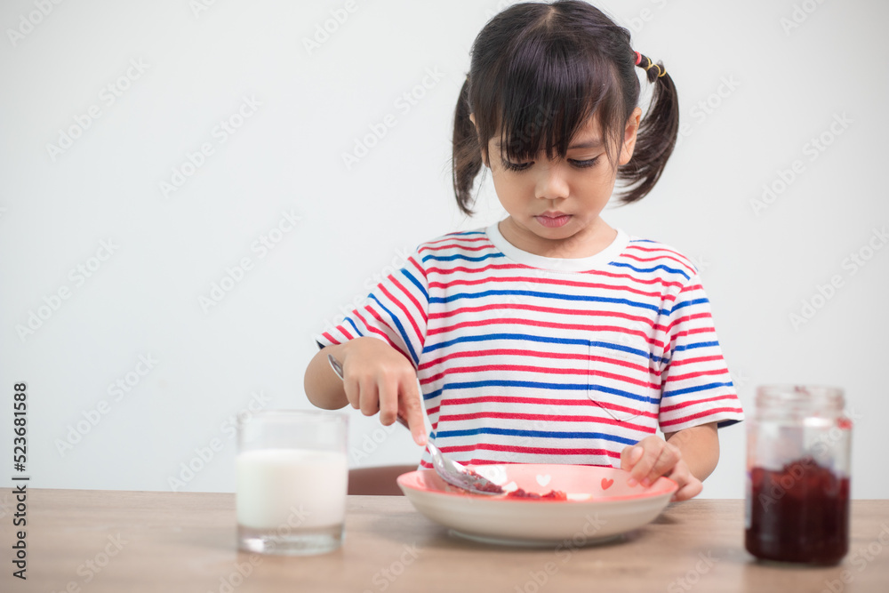 Asian girl having breakfast with bread and jam with a glass of milk Asian girl having breakfast with bread and jam with a glass of milk