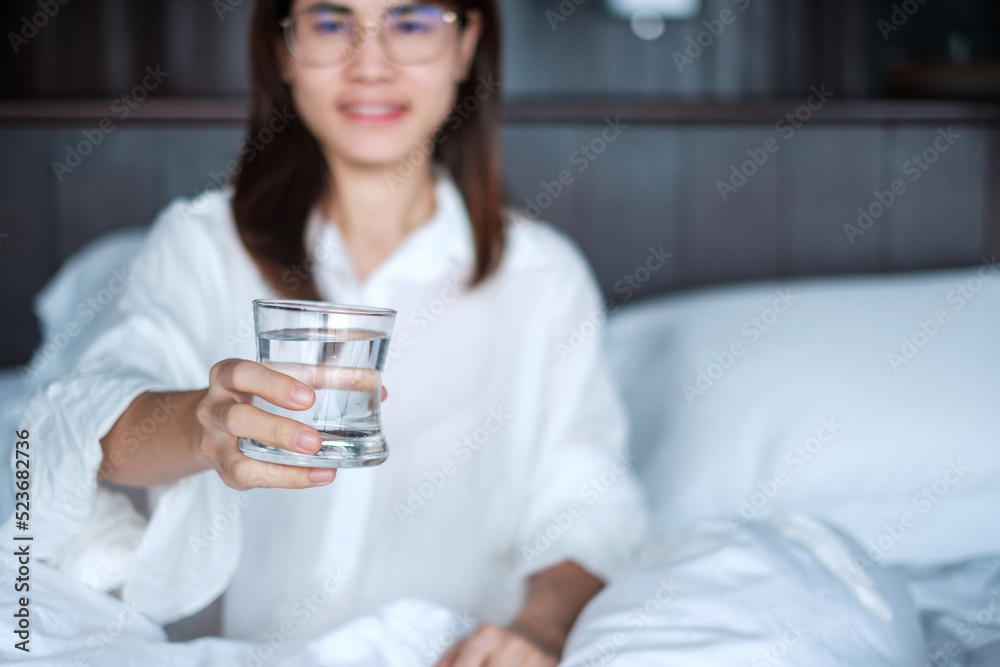 Happy woman holding water glass, female drinking pure water on bed at home. Healthy, Refreshment, lifestyle concept Happy woman holding water glass, female drinking pure water on bed at home. Healthy, Refreshment, lifestyle concept