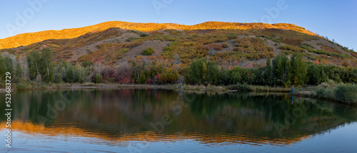 Sunlit hills, reflections in the Salt creek reservoir in Utah.