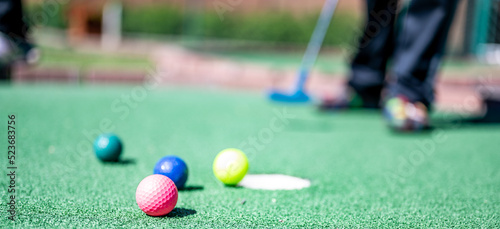 Mini golf game with several colored balls in the way of a putter lined up. photo