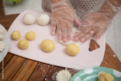 Female hands making dough for mooncake, homemade cantonese moon cake pastry on baking tray before baking for traditional festival. Travel, holiday, food concept