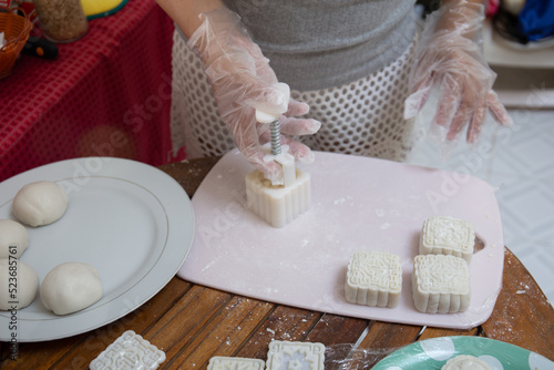 Making Mooncake. A mooncake is being moulded using plastic mould. The mould is being lifted  leaving the moulded mooncake on the board.