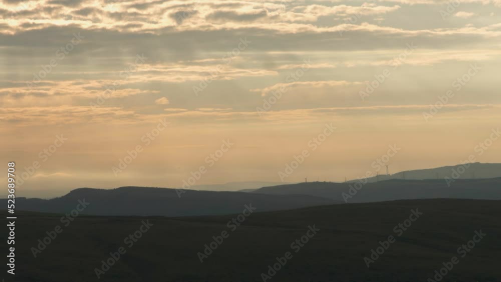 Sunrise Light Rays Shining Down on Wind Turbine Farm Landscape with Layers of Rolling Countryside Hills Wales UK 4K Sunrise Light Rays Shining Down on Wind Turbine Farm Landscape with Layers of Rolling Countryside Hills Wales UK 4K