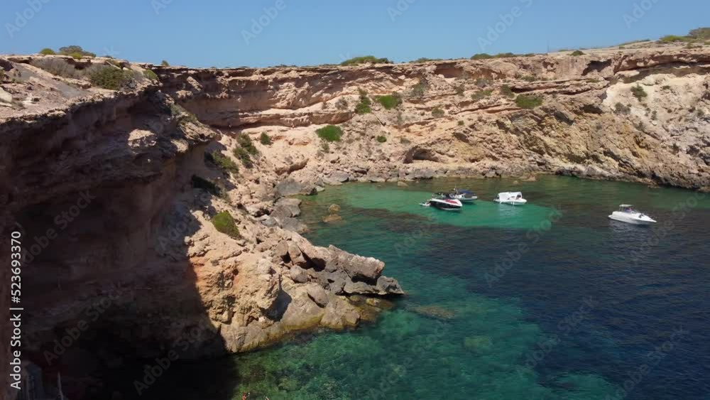 Most beautiful coves for swimming, chilling on IbizaDaring aerial view panorama curved flight drone footageof cliff edge beach Sa Figuera borda summer 2022