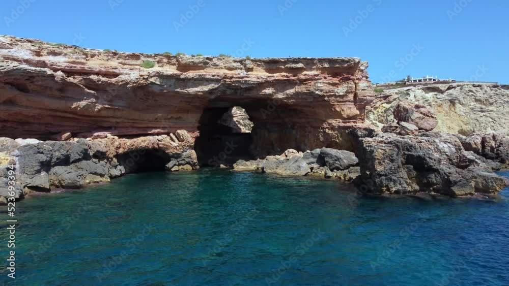 cliff edge secret pirate smuggler cave natural bridgeMarvelous aerial view flight fly forward drone footage to cave beach Sa Figuera borda Ibiza summer 2022 