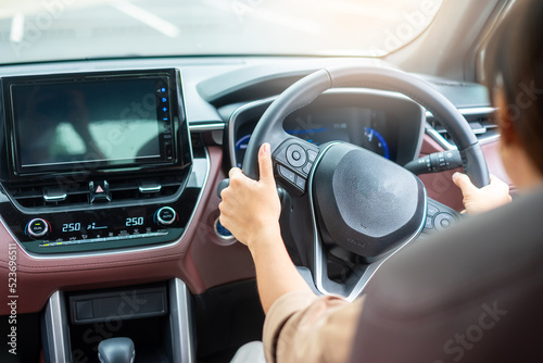 woman driver driving a car on the road, hand controlling steering wheel in electric modern automobile Fototapet