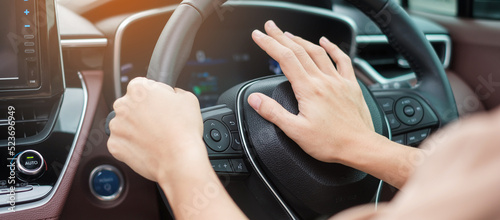Obraz na plátně woman driver honking a car during driving on traffic road, hand controlling steering wheel in vehicle