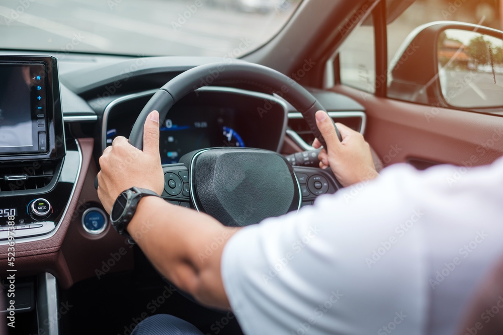 man driver driving a car on the road, hand controlling steering wheel in electric modern automobile. Journey, trip and safety Transportation concepts