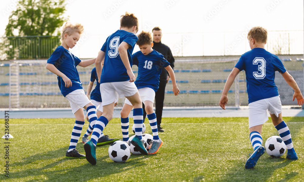 Obraz premium Happy Kids on Training Soccer Drill. Young European Footballers Dribbling Balls. Soccer Boys in Training With School Young Coach