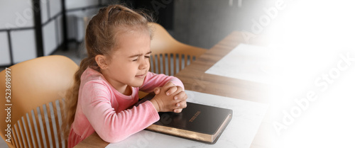 Little girl with Bible praying at home. Banner for design