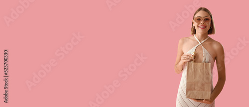 Pretty young woman with shopping bag on pink background with space for text