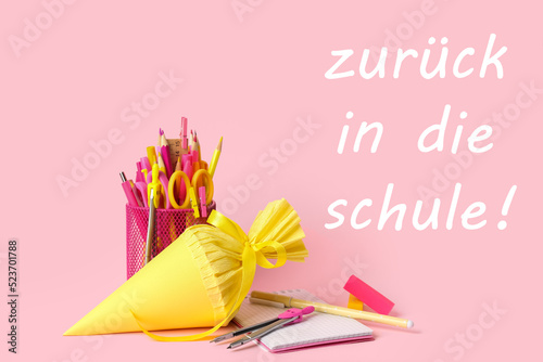 School cone and stationery on pink background. Zuruck in die schule (Back to school) photo