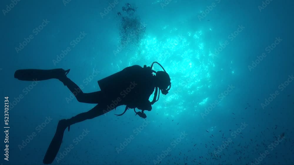 Silhouette of a scuba diver in full equipment below the ocean surface