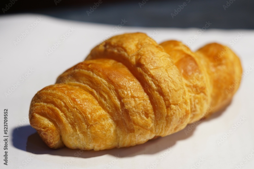 Golden yellow croissant, often paired with coffee. placed on white paper