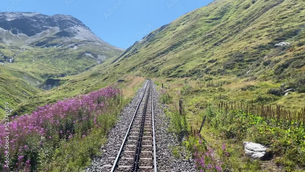 Steam railroad in the Swiss Alps goes over the Furka Pass with a toothed rack railroad. The old railroad line runs high above the mountains Steam railroad in the Swiss Alps goes over the Furka Pass with a toothed rack railroad. The old railroad line runs high above the mountains