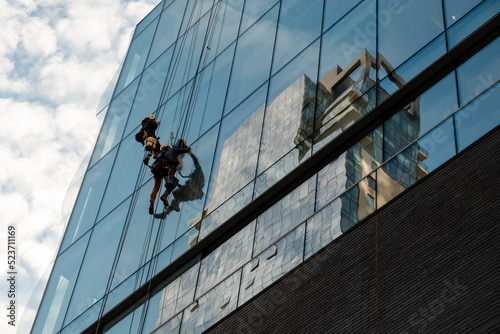 Workers cleaning office building windows. Industrial climbers wash the windows of a modern skyscraper. Men wash Windows on the evolution tower. Washers wash skyscraper windows sitting on hanging seats