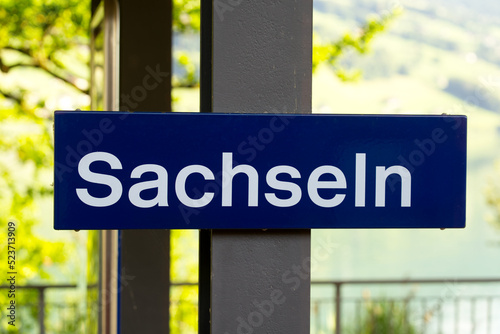 Blue sign at railway station Sachseln, Canton Obwalden, on a sunny summer day. Photo taken July 3rd, 2022, Sachseln, Switzerland.