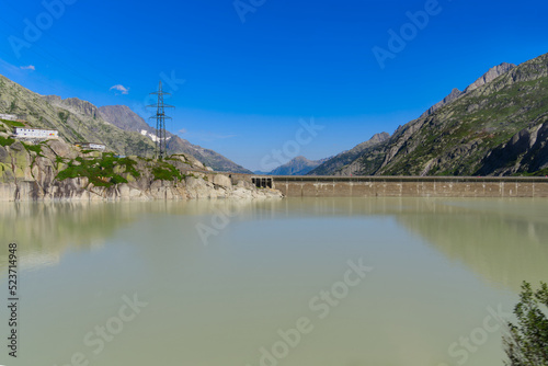 Scenic view of dam lake with mountain panorama in the background at Swiss mountain pass Grimsel on a sunny summer day. Photo taken July 3rd, 2022, Grimsel Pass, Switzerland.