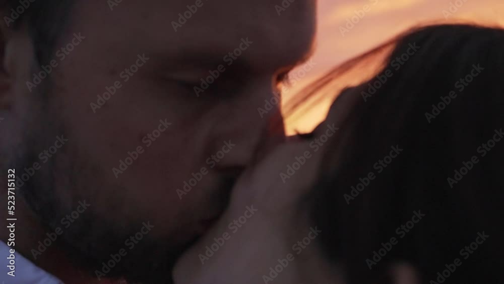 Couple kissing each other while the sun is setting behind them. Couple kissing each other while the sun is setting behind them.