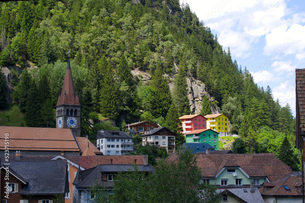 Mountain village Göschenen with beautiful colored houses and church tower on as sunny summer day. Photo taken July 3rd, 2022, Göschenen, Switzerland.